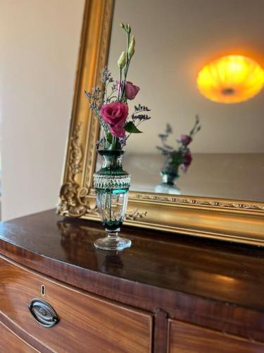 a vase with flowers on a dresser in front of a mirror at Manoir Nestor - Chairière in Vresse-sur-Semois