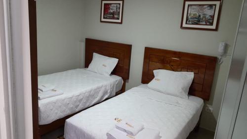 2 camas en una habitación de hotel con sábanas blancas en HOSTAL IMPERIO KALLPA, en Chachapoyas