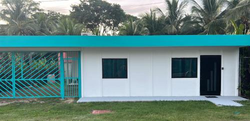 une petite maison blanche avec un toit bleu dans l'établissement Cahuita Apartment by Angie, à Cahuita