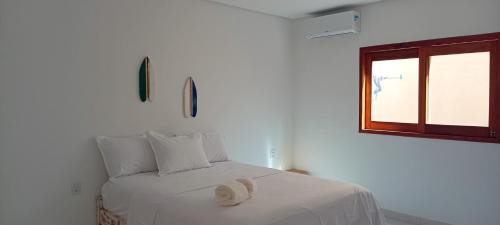 een witte slaapkamer met een bed met een hoed erop bij Cafofo Prea in Cruz