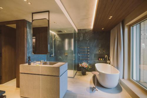 ein Badezimmer mit einer großen Badewanne und einem Waschbecken in der Unterkunft Adults Only Hotel Reiters Supreme in Bad Tatzmannsdorf