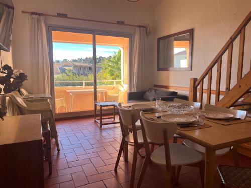 a dining room with a table and chairs and a window at L'Appartement des Sables in Le Lavandou