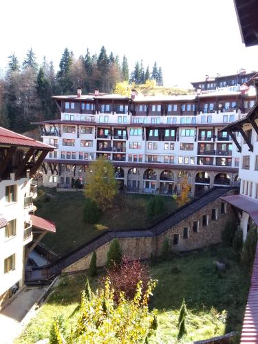 a large white building with trees in the background at Апартамент за гости 4а26 Планинска Магия Grand Monastery Пампорово in Pamporovo