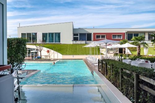 una piscina con sedie e ombrelloni accanto a un edificio di Domino Suite Hotel & Residence a Lido di Jesolo