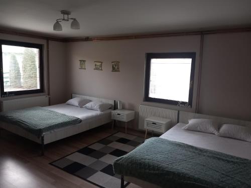 a bedroom with two beds and two windows at Guest house Dagovic in Bajina Bašta
