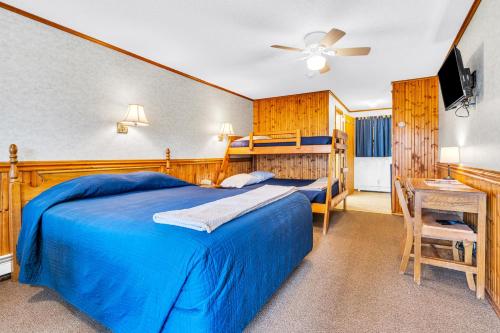 a bedroom with a blue bed and a desk at The Inn at the Rostay in Bethel