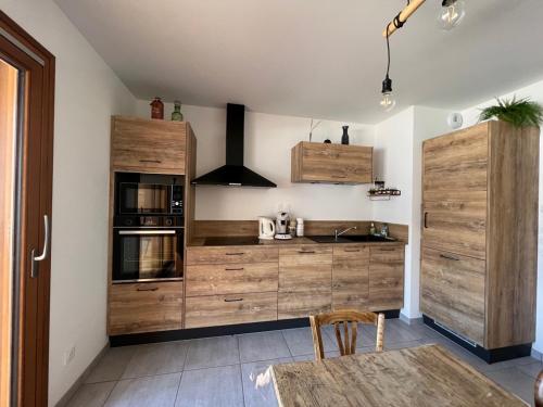 une cuisine avec des placards en bois et une table dans l'établissement Appartement 3 Pièces, 6 Pers., Terrasse, Jardin, Parking, Proche Pistes et Navette, Serre Chevalier - FR-1-762-51, au Monêtier-les-Bains