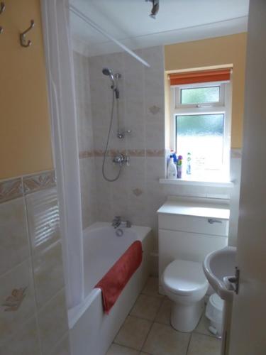 een badkamer met een bad, een toilet en een douche bij Sea view bungalow in The Mumbles