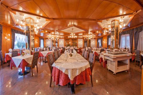 a dining room with tables and chairs and chandeliers at Hotel Cristallo in Andalo