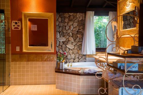 a bathroom with a tub and a stone wall at Maua Brasil Hotelaria in Visconde De Maua