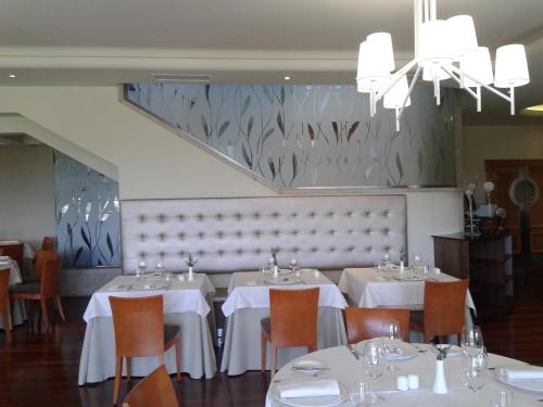 a dining room with white tables and chairs and a chandelier at Gran Hotel Los Abetos in Santiago de Compostela