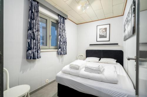 um quarto com uma cama com lençóis brancos e cortinas azuis em Casa Elise em Westouter
