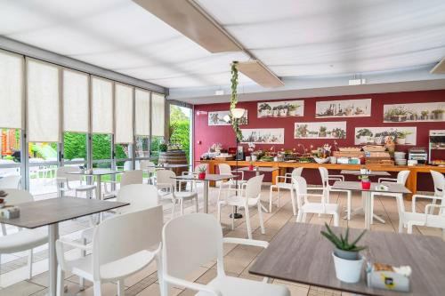 un restaurant avec des tables et des chaises blanches et des murs rouges dans l'établissement Domino Suite Hotel & Residence, à Lido di Jesolo