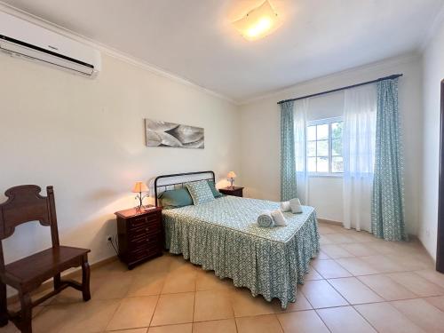 1 dormitorio con 1 cama, 1 silla y 1 ventana en Villa Entrecolinas, en São Bartolomeu de Messines