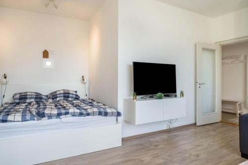 een witte slaapkamer met een bed en een flatscreen-tv bij Ferienwohnung Kieler Altstadt in Kiel