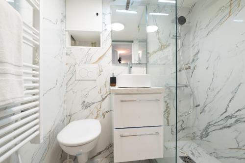 une salle de bain blanche avec toilettes et douche dans l'établissement Rooftops of Paris l Opéra - Madeleine, à Paris