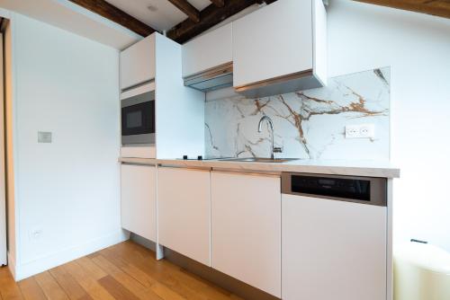 une cuisine avec des armoires blanches et un évier dans l'établissement Rooftops of Paris l Opéra - Madeleine, à Paris