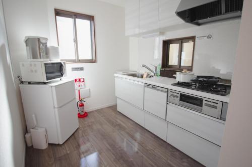 a white kitchen with a sink and a microwave at QiQi House Serenity 新築一軒家宿 Brand New Exclusive 3-Story House Near Tokyo Skytree Asakusa in Tokyo