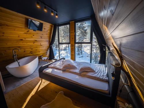 a bedroom with a tub and a bed and a window at Black Chalet in Vartop