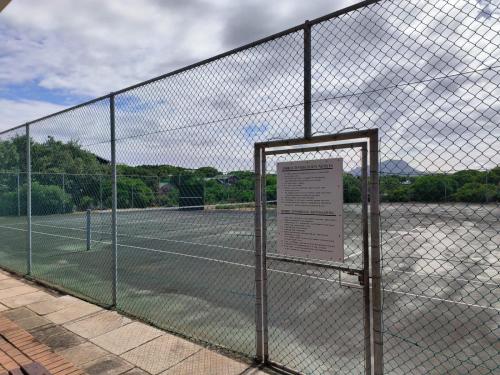 a chain link fence with a tennis court at Strictly-Halaal Holiday Home at Meerensee Resort in Fisherhaven