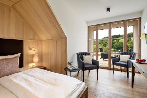 a bedroom with a bed and a desk and chairs at Gutshofhotel Winkler Bräu in Lengenfeld