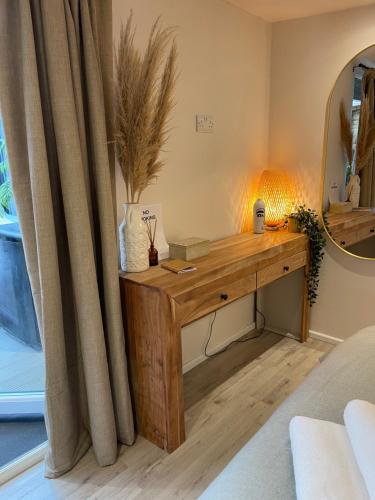 escritorio de madera en una habitación con espejo en El Nido - Self Catering cabin in Southbourne, 5 mins from beach en Iford
