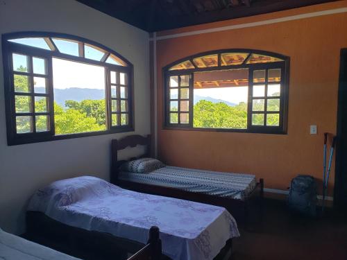 two beds in a room with two windows at Pousada e Hostel Casa da Jura in Ilhabela
