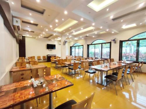 a restaurant with wooden tables and chairs and windows at HOTEL NATURE SHIELD in Lonavala