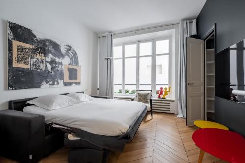 une chambre avec un lit et une grande fenêtre dans l'établissement Veeve - Orsay Artistry, à Paris