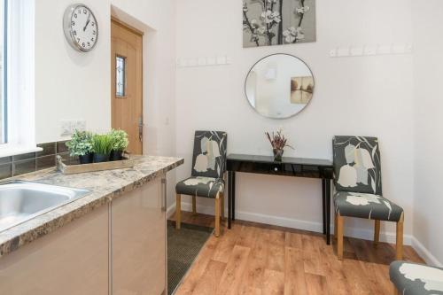 a kitchen with two chairs and a sink and a mirror at Stables in Melrose