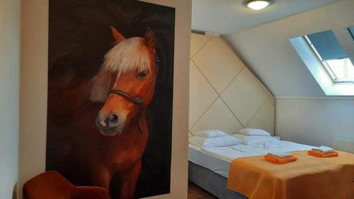 a painting of a horse next to a bed at Caballus Lovasmajor in Nyíregyháza