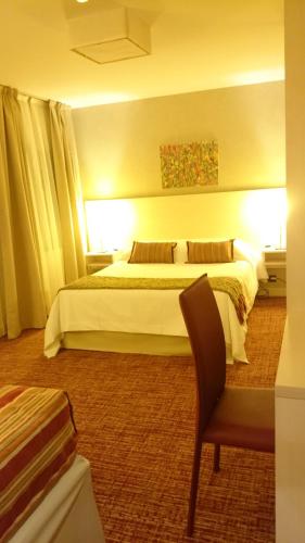 a hotel room with a bed and a chair at Hotel De Los Andes in Ushuaia
