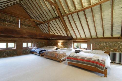 a large room with three beds and a stone wall at Barn conversion, Henley-on-Thames in Henley on Thames