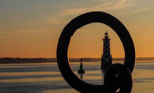 a view of a lighthouse in the water at sunset at ARVEIL in Plomeur
