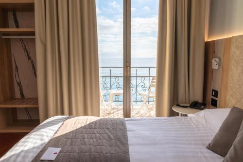 a bedroom with a bed and a view of the ocean at Hotel Parigi & Spa in Bordighera
