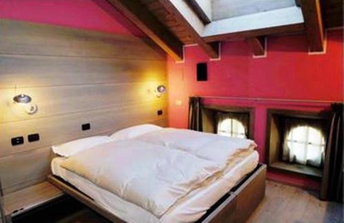 - un grand lit dans une chambre avec un mur rose dans l'établissement Residence Hotel Serenella, à Aprica