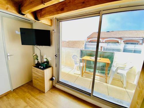 Pokój z dużym oknem ze stołem i telewizorem w obiekcie ''Ophélia 133'' Cosy studio climatisé avec balcon w mieście Sète