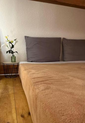 - un lit avec 2 oreillers et un vase avec des fleurs dans l'établissement ''Ophélia 133'' Cosy studio climatisé avec balcon, à Sète