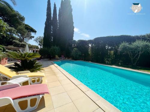 - une piscine avec des chaises et des arbres jaunes et roses dans l'établissement Mazet Cocagne, à Sainte-Maxime