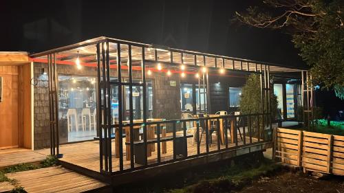 a glass house with a deck at night at QUELEN AUSTRAL in Hornopiren