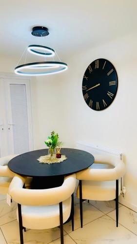 a dining room with a table and a clock on the wall at Mo Apartment in Accrington