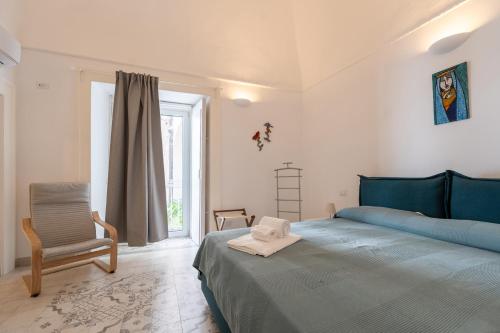 a bedroom with a blue bed and a chair at La Piccola Atrani in Atrani