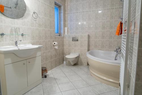 uma casa de banho com um lavatório, uma banheira e um WC. em Penzion U rybníka em Šumperk