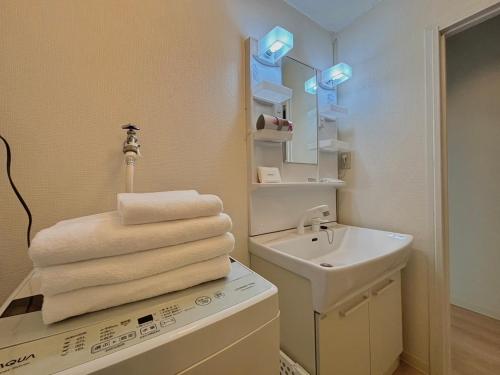 a bathroom with a sink and a pile of towels at Neighbor's Hotel 十日市 in Hiroshima