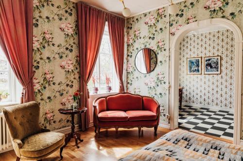 a living room with a red chair and floral wallpaper at Hotell Park in Västervik