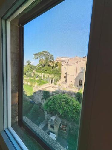 a window with a view of a building and trees at Volaterrae Deluxe Loft with garden in Volterra