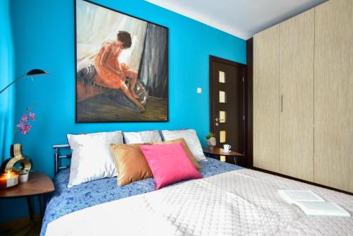 a blue bedroom with a bed with a painting on the wall at Central Warsaw Pol in in Warsaw