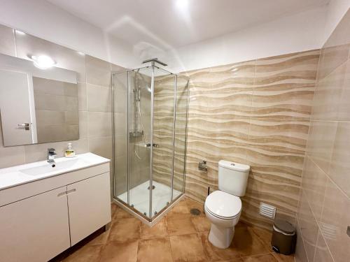 y baño con ducha, aseo y lavamanos. en Villa Entrecolinas en São Bartolomeu de Messines