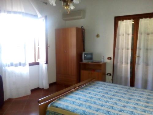 a bedroom with a bed and a television and a window at B&B Il Vigneto in Capoterra