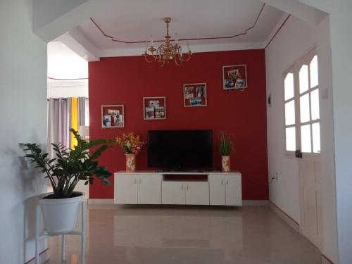 een woonkamer met een tv en een rode muur bij Chez Leonilde in São Filipe